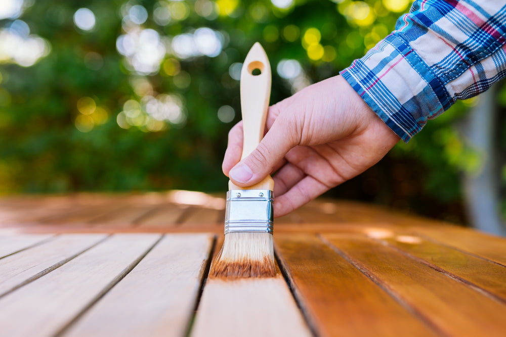 A man painting a wooden gate