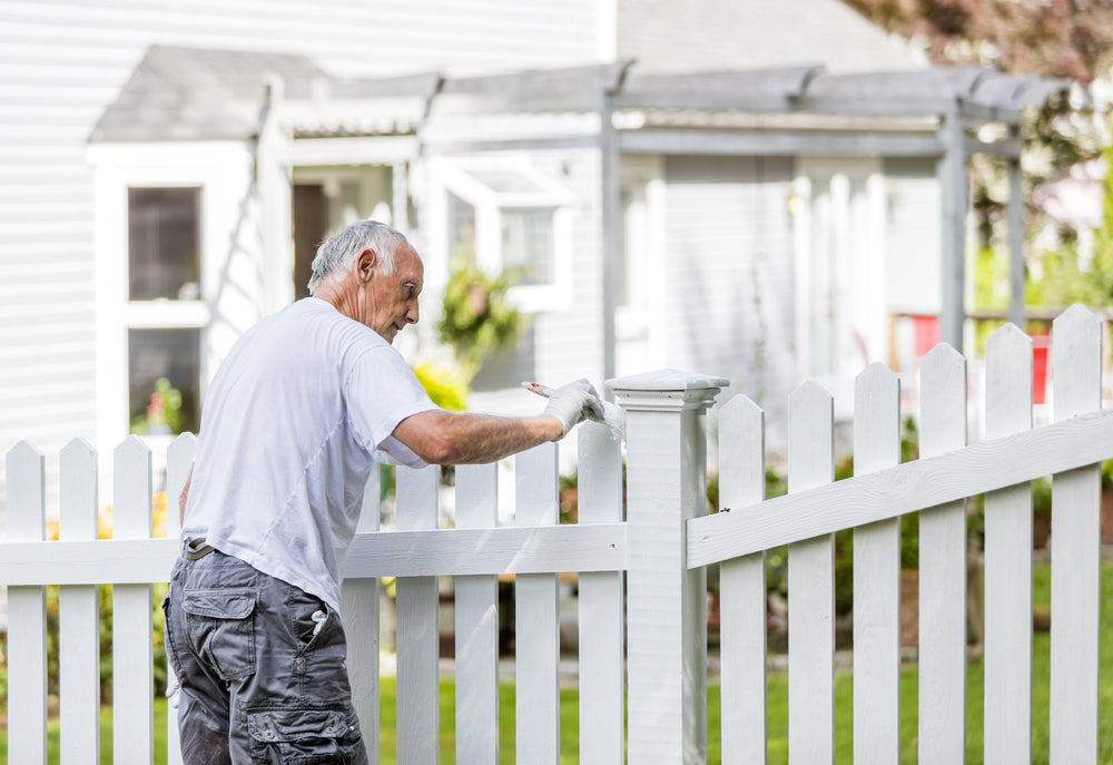 man painting wooden gate