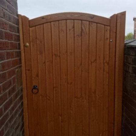 A reddish brown single garden gate with a curved top