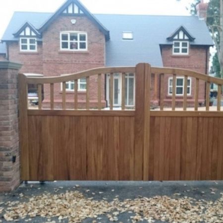 A large wooden double driveway gate with a curved top